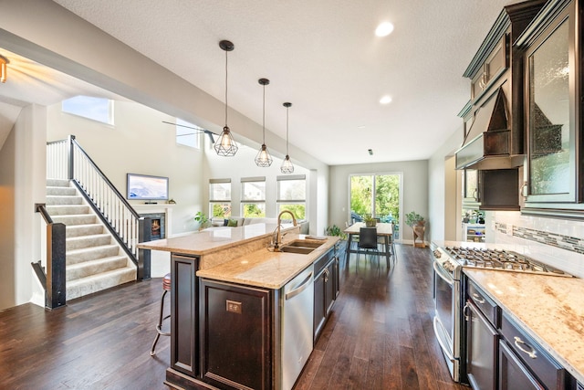 kitchen with a sink, dark wood finished floors, open floor plan, stainless steel appliances, and decorative backsplash