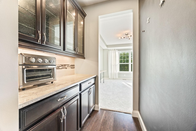 bar with baseboards, backsplash, dark wood finished floors, and a toaster