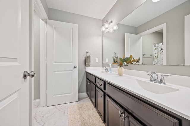 bathroom featuring a sink, baseboards, marble finish floor, and double vanity