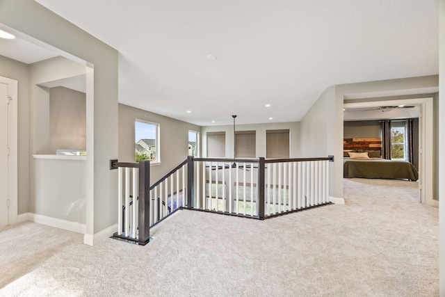 hallway with an upstairs landing, plenty of natural light, and carpet