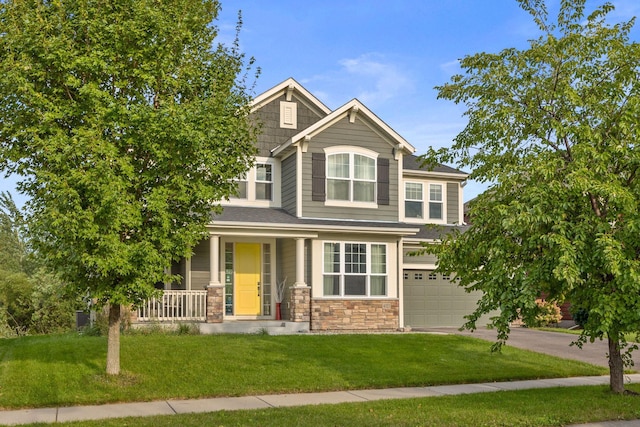 craftsman house featuring a front lawn, covered porch, stone siding, and driveway