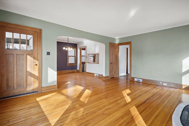 foyer with light wood-type flooring, visible vents, arched walkways, and a notable chandelier