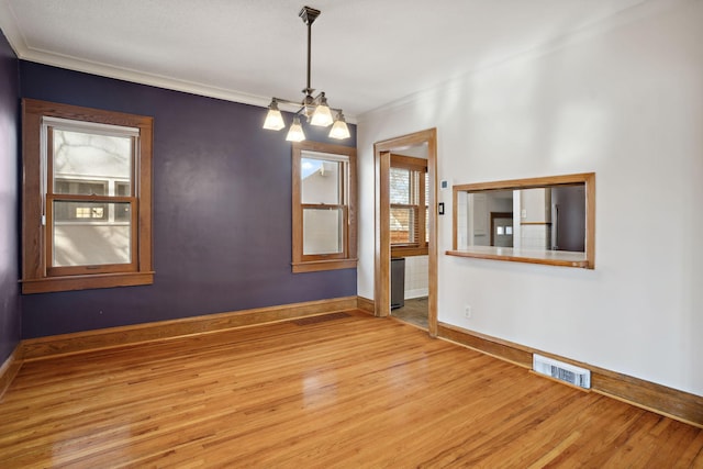 unfurnished room with a notable chandelier, wood finished floors, visible vents, and baseboards