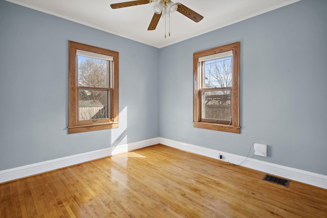 unfurnished room with visible vents, a ceiling fan, baseboards, and wood finished floors