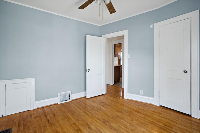 unfurnished bedroom featuring light wood finished floors, visible vents, crown molding, and baseboards