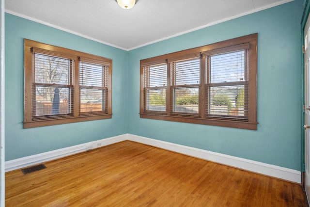 empty room featuring visible vents, baseboards, and wood finished floors