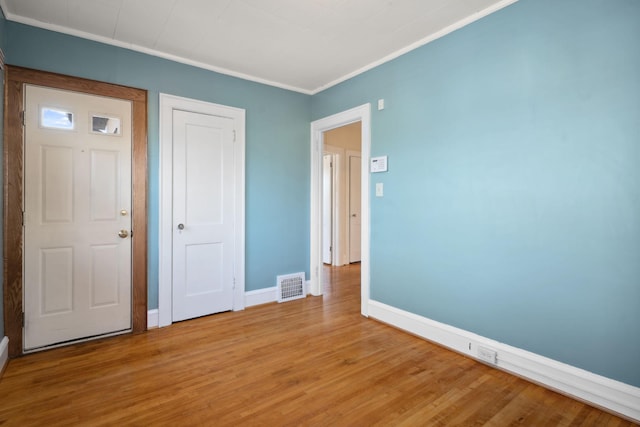 interior space featuring visible vents, light wood-style flooring, baseboards, and ornamental molding