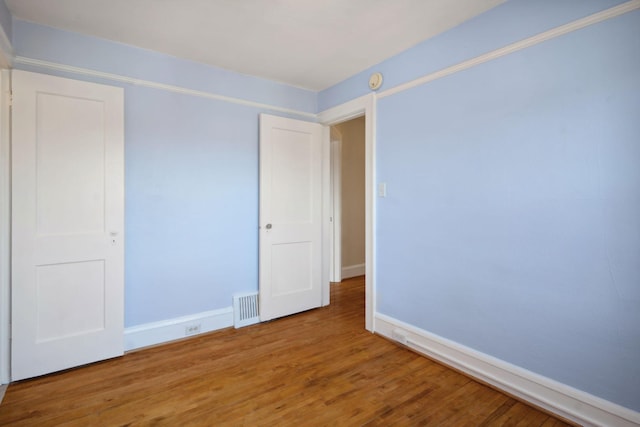 unfurnished room featuring visible vents, baseboards, and wood finished floors