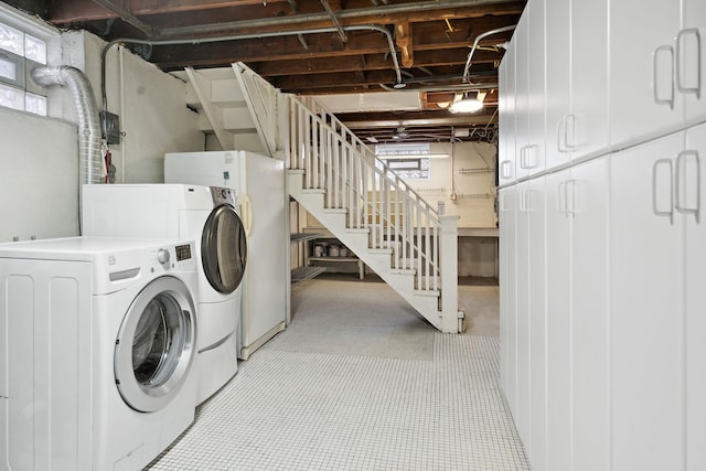 clothes washing area featuring separate washer and dryer and cabinet space