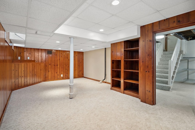 finished basement with recessed lighting, carpet floors, wooden walls, baseboards, and stairs