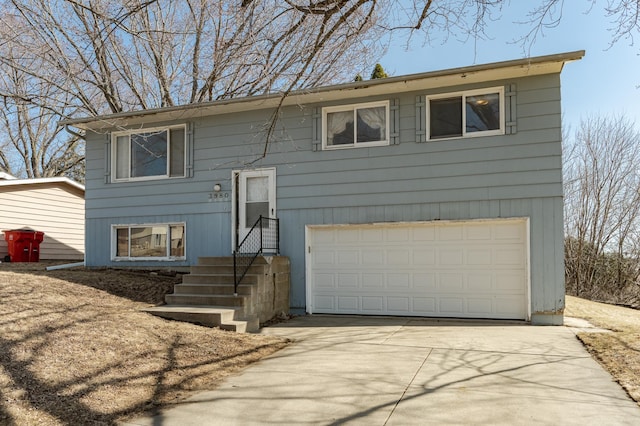 bi-level home featuring an attached garage and concrete driveway