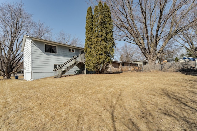 back of property featuring stairs, fence, a lawn, and a wooden deck