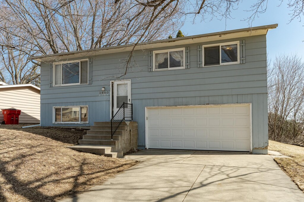 bi-level home featuring driveway, an attached garage, and entry steps
