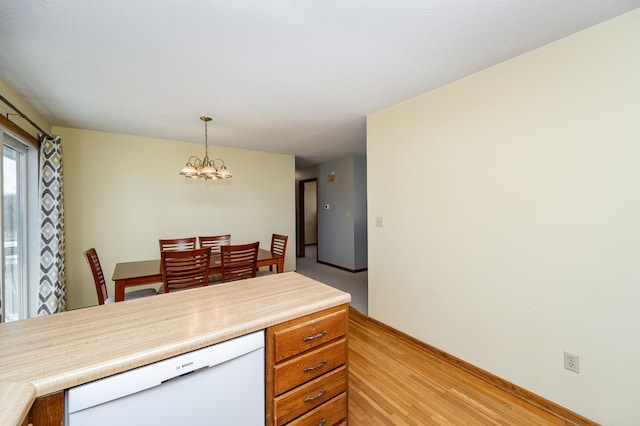 kitchen featuring a chandelier, decorative light fixtures, dishwasher, light countertops, and light wood-style flooring