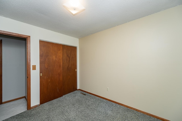 unfurnished bedroom with a closet, carpet flooring, a textured ceiling, and baseboards