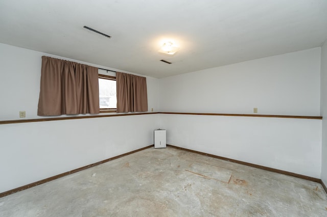 spare room featuring visible vents, unfinished concrete flooring, and baseboards