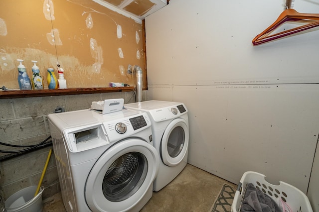 washroom featuring washing machine and clothes dryer, laundry area, and concrete block wall