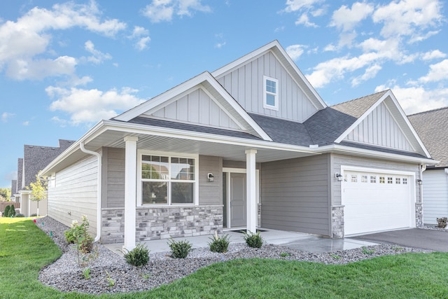 view of front of home featuring board and batten siding, a front yard, roof with shingles, stone siding, and driveway