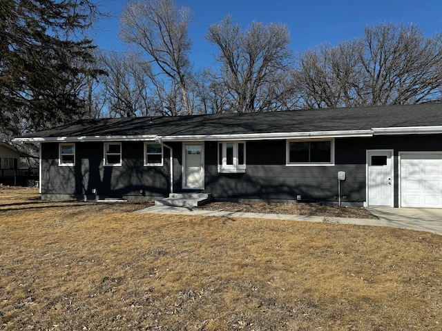 ranch-style house featuring concrete driveway, an attached garage, and a front lawn