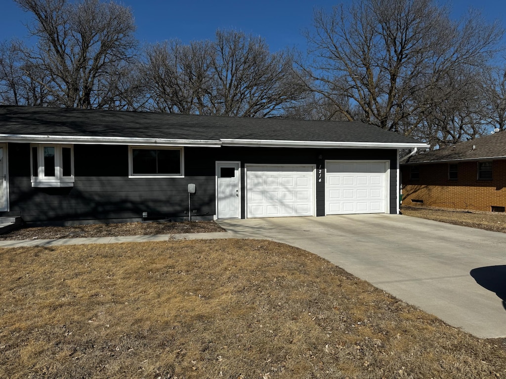 ranch-style house with an attached garage, driveway, and a shingled roof