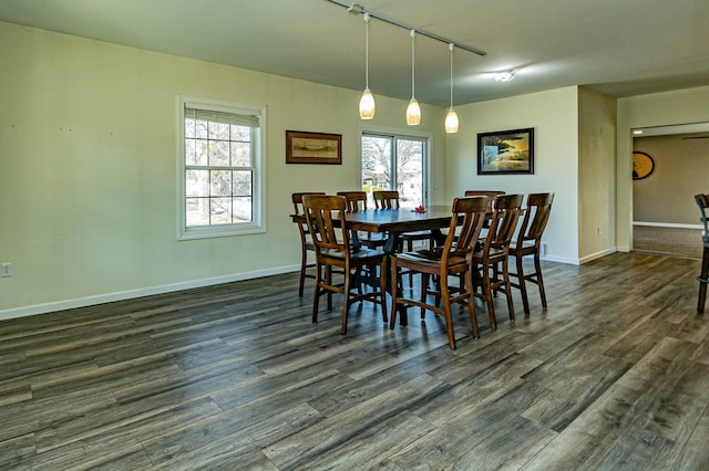 dining space with baseboards, dark wood finished floors, and track lighting