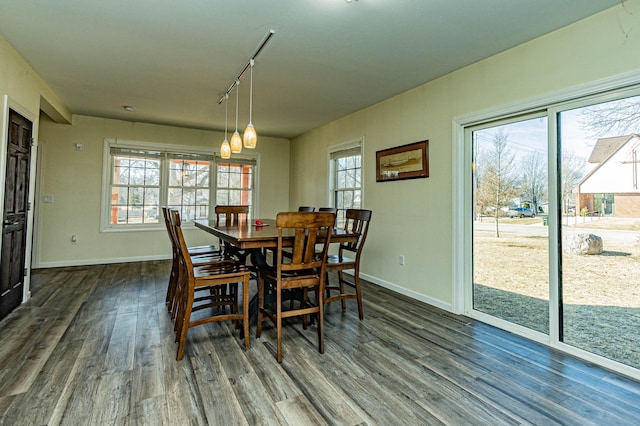 dining space with track lighting, dark wood-style floors, and baseboards