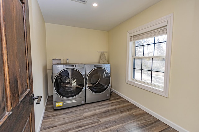 clothes washing area featuring baseboards, washing machine and dryer, laundry area, recessed lighting, and wood finished floors