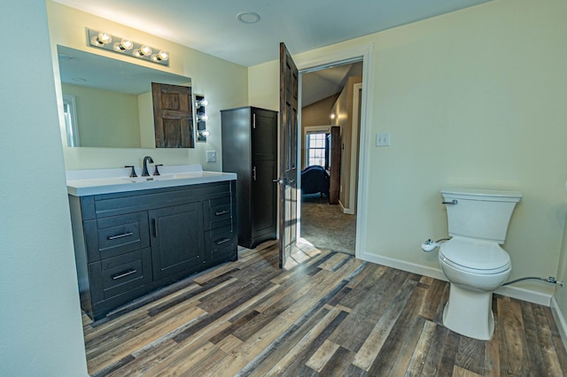 bathroom with toilet, vanity, baseboards, and wood finished floors