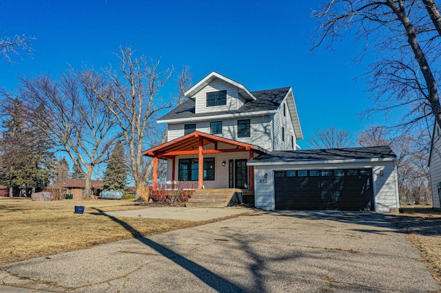 traditional style home featuring a porch, an attached garage, a front lawn, and driveway