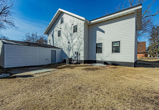 back of house featuring central air condition unit and a yard