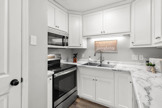 kitchen featuring white cabinetry, light stone countertops, appliances with stainless steel finishes, and a sink