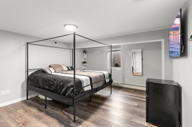 bedroom featuring a baseboard radiator, baseboards, and wood finished floors