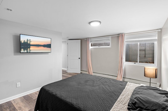 bedroom featuring baseboard heating, baseboards, and wood finished floors