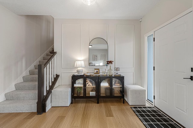 entrance foyer featuring stairs, wood finished floors, and a textured ceiling