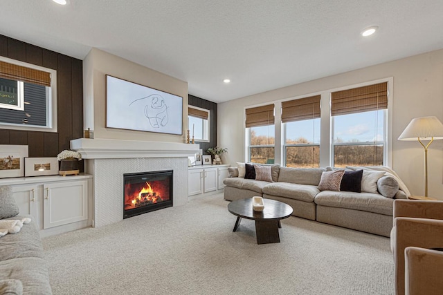 living room with a textured ceiling, carpet flooring, recessed lighting, and a tile fireplace