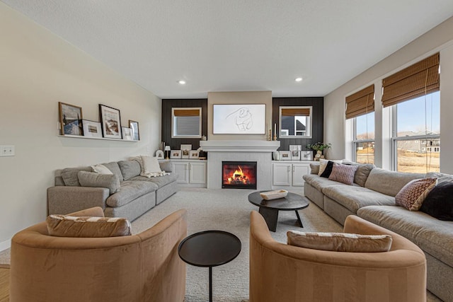 living room featuring recessed lighting, light colored carpet, a glass covered fireplace, and a textured ceiling