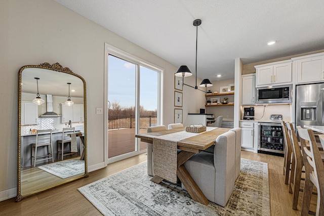 dining area featuring recessed lighting, light wood-type flooring, baseboards, and beverage cooler