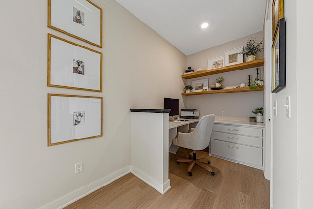 office space with baseboards, built in study area, vaulted ceiling, and light wood finished floors