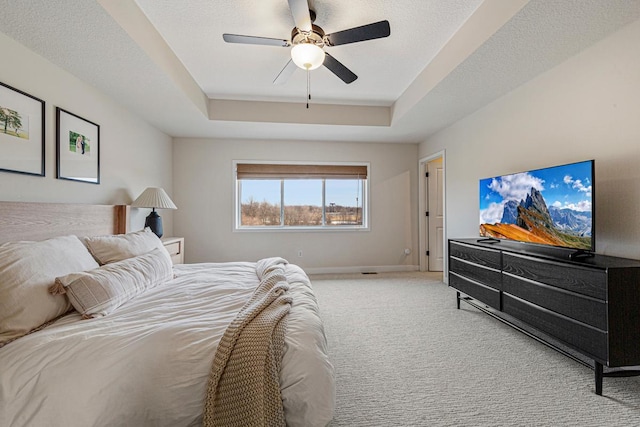 bedroom with a ceiling fan, baseboards, a tray ceiling, a textured ceiling, and carpet flooring