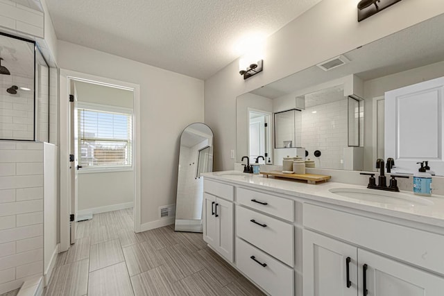 bathroom with visible vents, a tile shower, and a sink