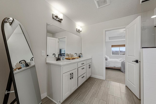 ensuite bathroom featuring visible vents, double vanity, ensuite bath, a sink, and a textured ceiling