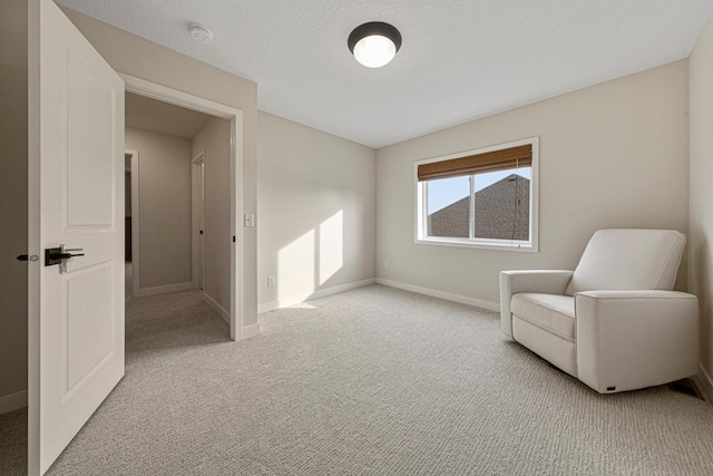 sitting room with baseboards, light colored carpet, and a textured ceiling