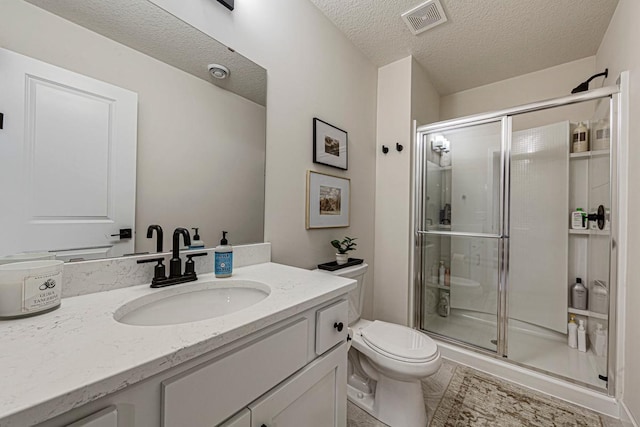 bathroom with vanity, a shower stall, toilet, and visible vents