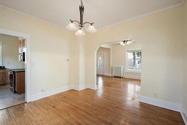 unfurnished dining area with ornamental molding, hardwood / wood-style flooring, arched walkways, radiator, and baseboards