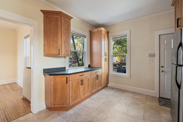 kitchen with baseboards, dark countertops, crown molding, and freestanding refrigerator