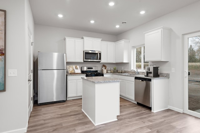 kitchen featuring white cabinets, appliances with stainless steel finishes, a center island, and light wood-type flooring