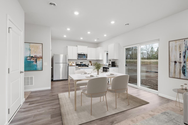 dining space with light wood-style flooring, recessed lighting, visible vents, and baseboards