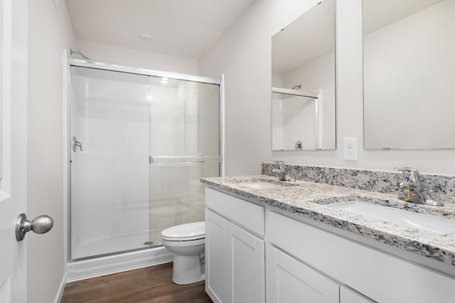 full bath featuring toilet, wood finished floors, a stall shower, and a sink