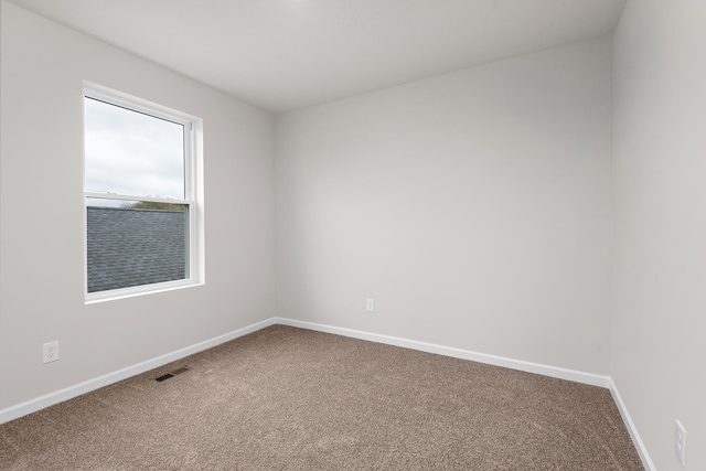 carpeted spare room featuring visible vents and baseboards