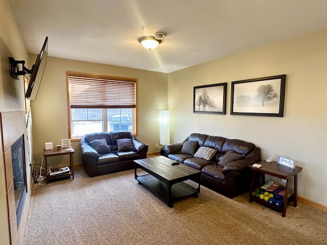 carpeted living room with a glass covered fireplace and baseboards